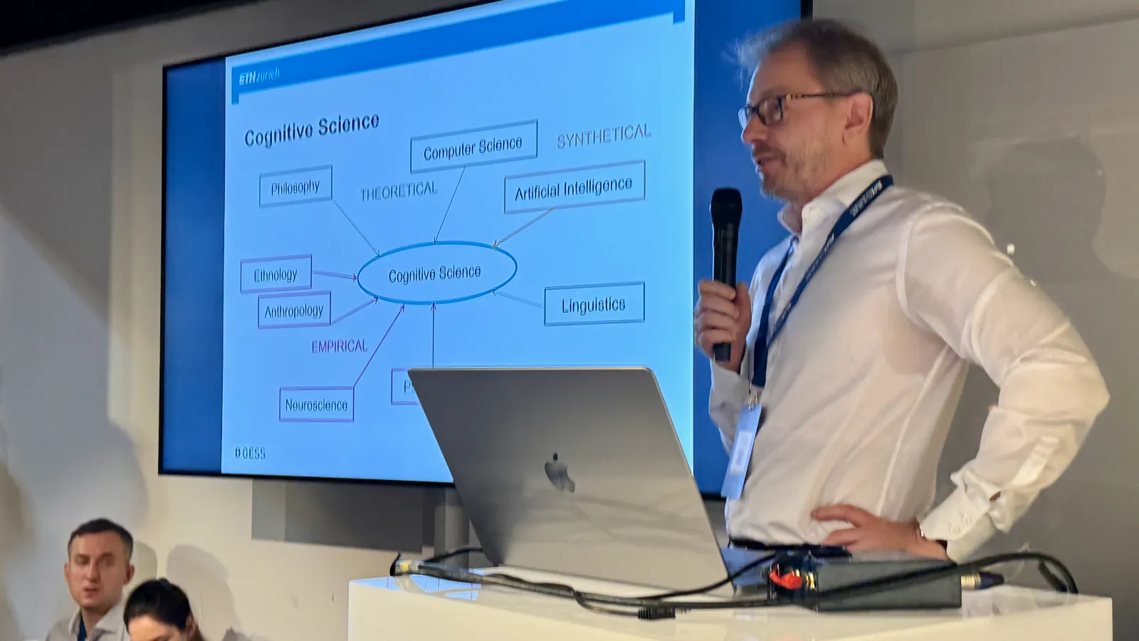 Christoph Hoelscher at the lectern, a cognitive science diagram on the screen behind him