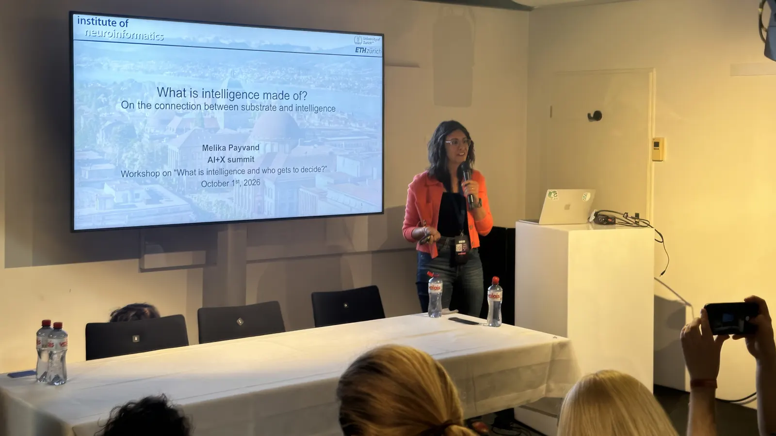 Melika Payvand beside her title slide “What is intelligence made of?”
