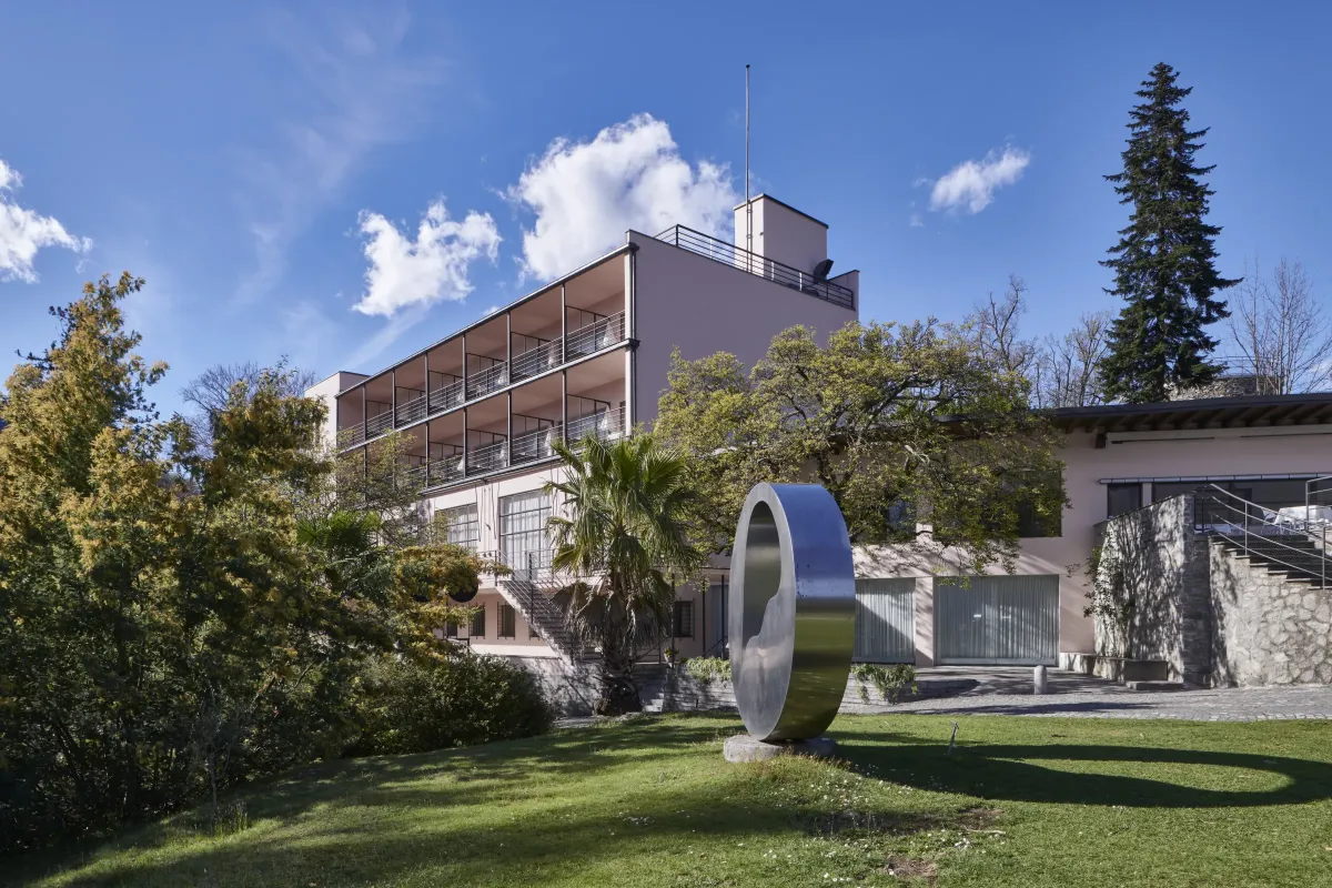 Monte Verità, Ascona: the hotel building above the garden lawn, with a steel ring sculpture